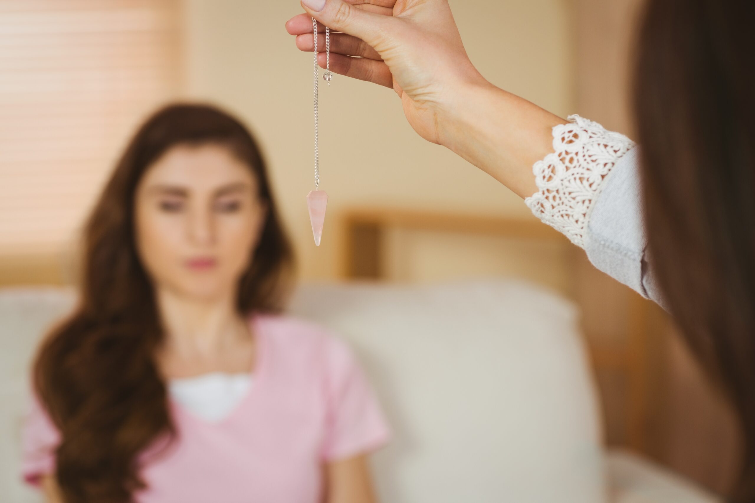 Hypnotherapist holding pendulum before her patient Hypnotherapist holding pendulum before her patient